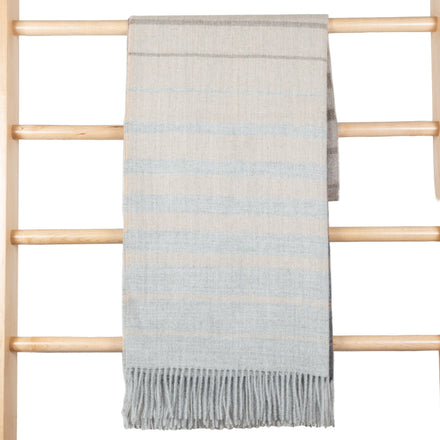 Striped blanket hanging on a wooden ladder against a white wooden panel background