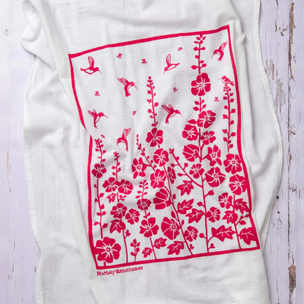 White dish towel with red floral pattern on a wooden surface