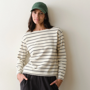 Woman wearing a black and white striped long sleeved shirt on a neutral background.