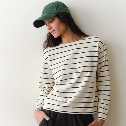 Woman wearing a black and white long sleeved tee on a neutral background.